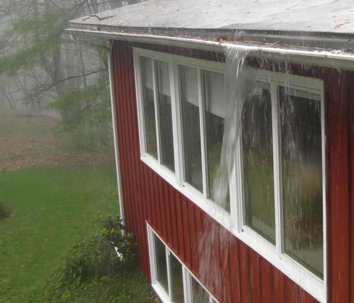 Rain pouring down on the roof of a home.